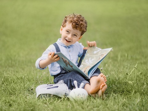 Child on a lawn reading a book
